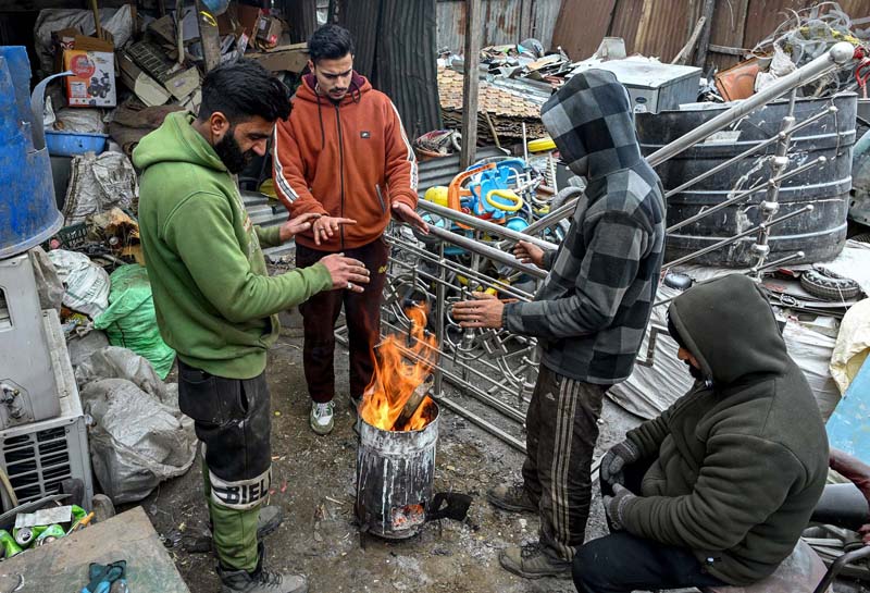 People warm themselves around fire as Valley remains under the grip of harsh winter.-Excelsior/Shakeel
