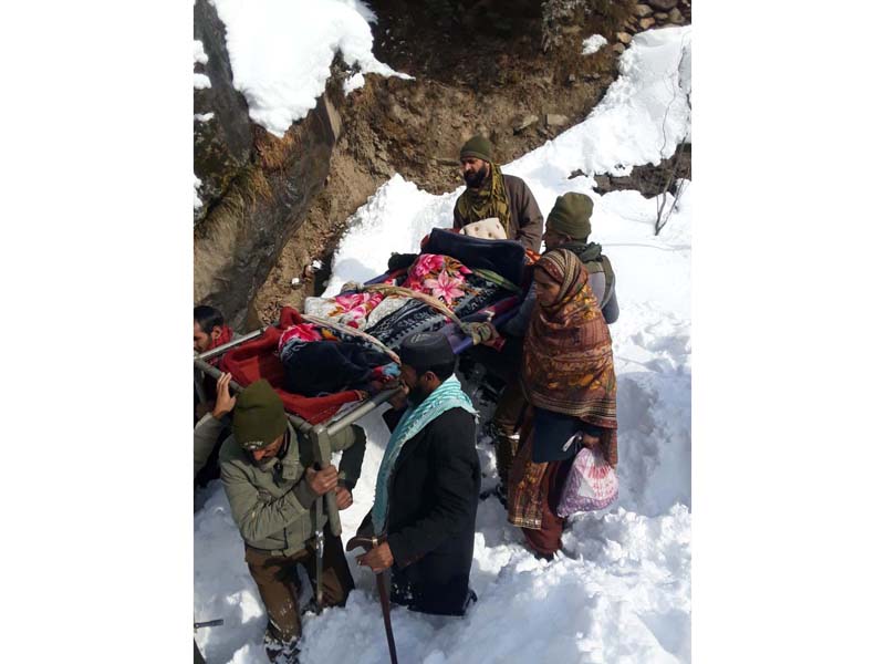 A patient being brought to hospital from Bhallesa area on cot by cops as road was closed due to heavy snowfall.-Excelsior/Rafi Choudhary